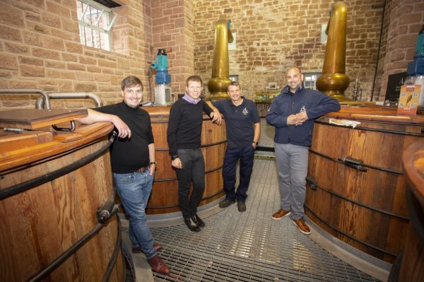 Dr Markus Rondé and Dr Adam Robinson with Annandale Distillery's Mark Trainor and David Ashton. The men are standing in Annandale Distillery and are leaning against wooden vats