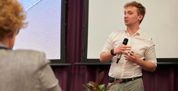 Sebastiaan Schalkwijk, Founder of Solarsub standing in a room speaking to a group of people, holding a microphone