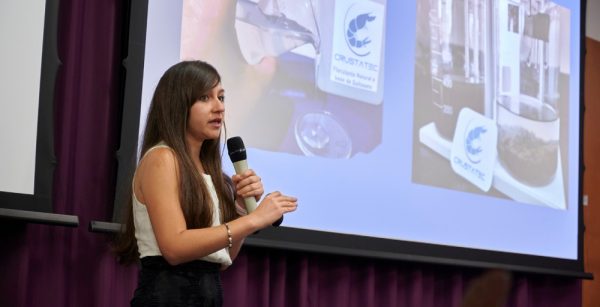 María Isabel Amorín, Founder, CrustaTec presenting content on a large screen and holding a microphone