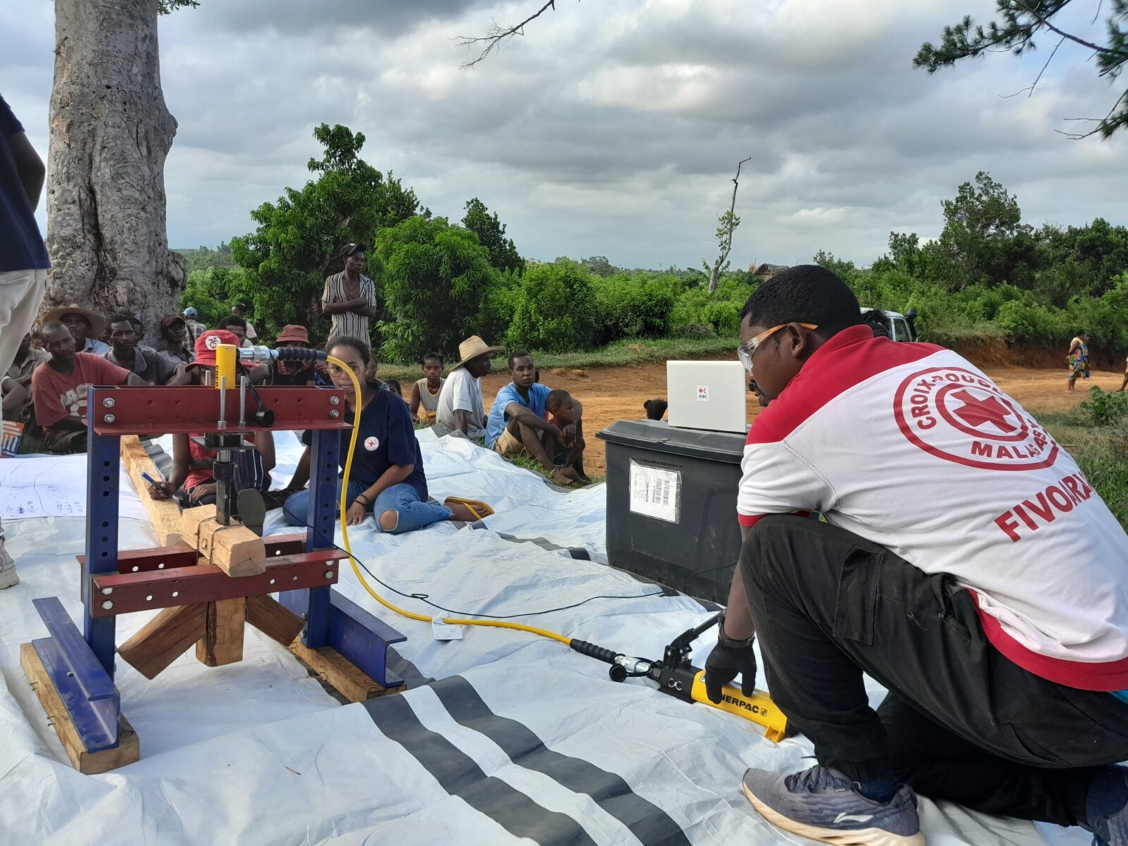 A member of the Malagasy Red Cross carrying out a structural test while local people observe